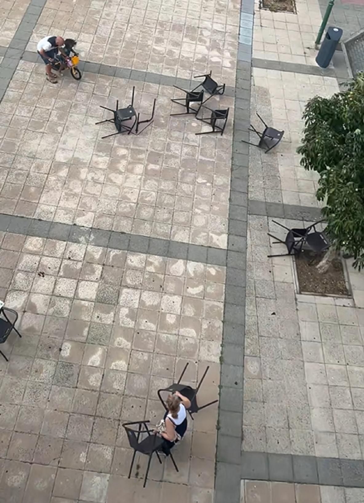 Las fuertes rachas de viento levantan las sillas de la terraza de un bar, que salen despedidas mientras varios clientes intentan evitar que terminen en la carretera.