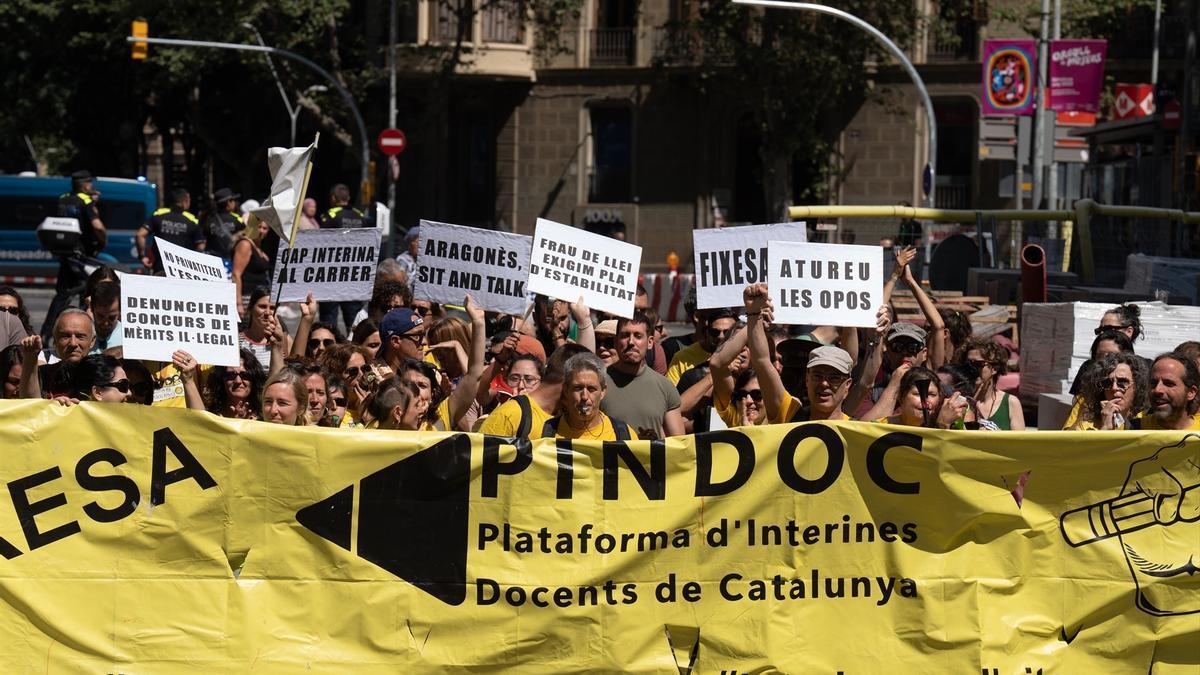 Varias personas con carteles durante una manifestación de docentes interinos, a 12 de junio de 2023.