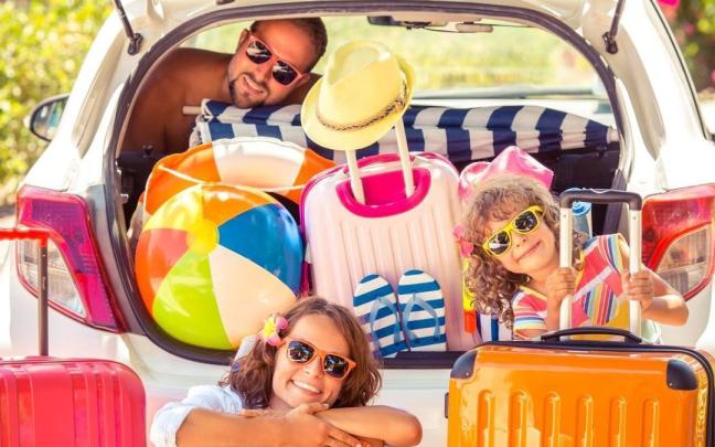 Una familia posa en su coche antes de irse de vacaciones.