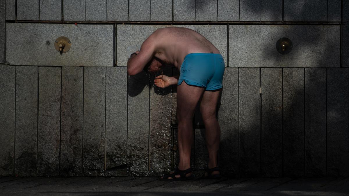 Una persona se refresca en una fuente, en Madrid.