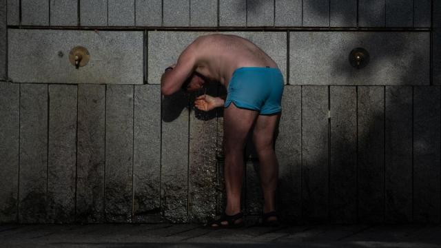 Una persona se refresca en una fuente, en Madrid.