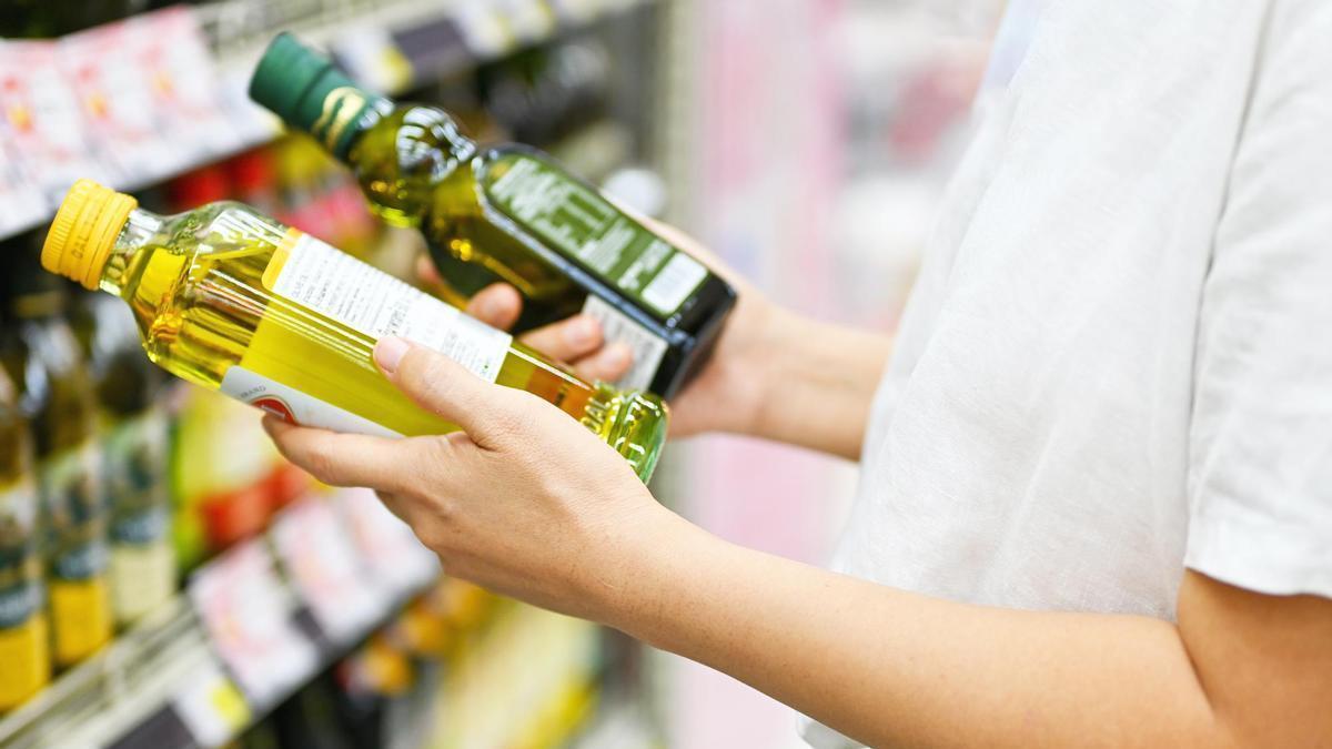 Una mujer, con dos botellas de aceite de oliva en un supermercado.