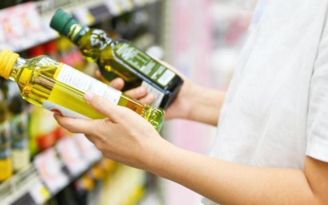 Una mujer, con dos botellas de aceite de oliva en un supermercado.