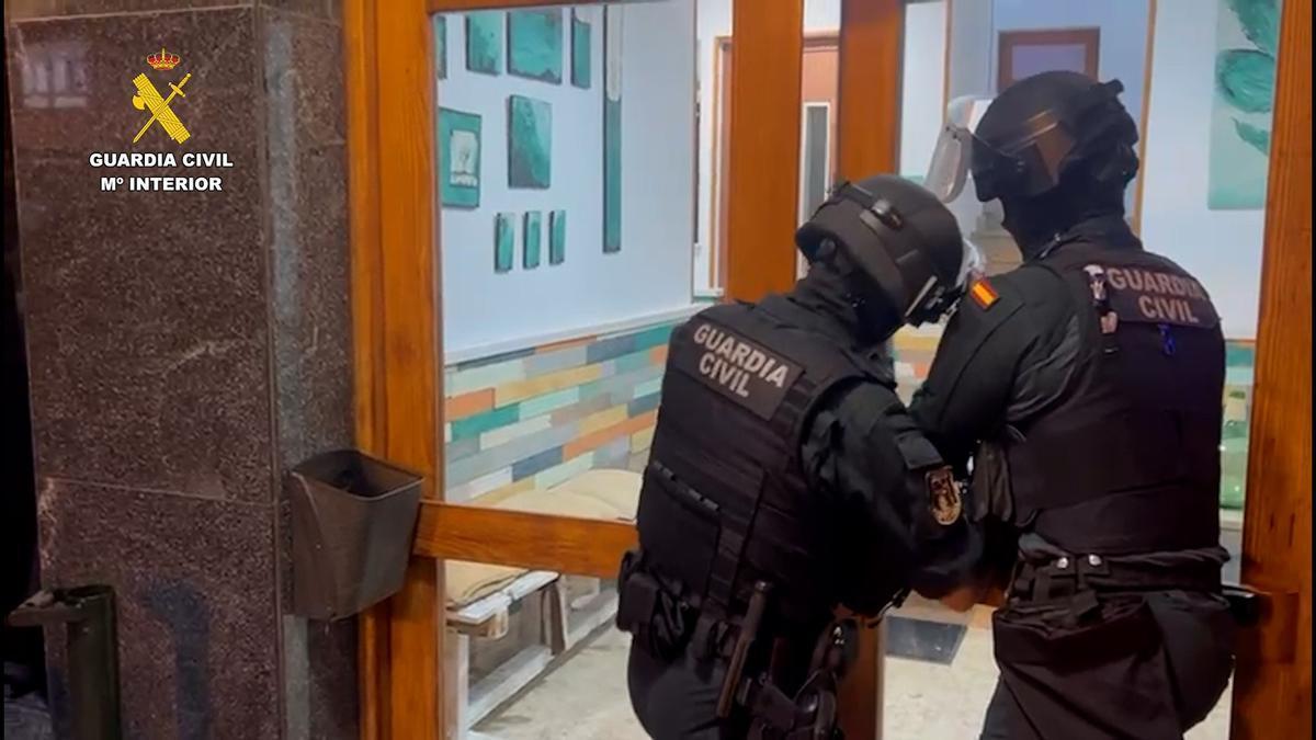 Dos agentes de la Guardia Civil acceden al portal de uno de los domicilios registrados en el marco de la 'operación Network'.
