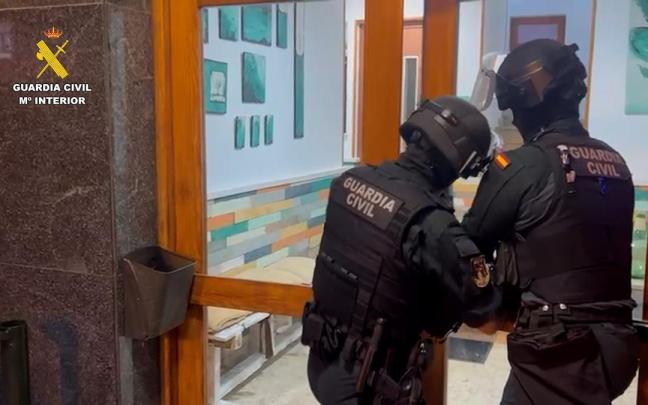 Dos agentes de la Guardia Civil acceden al portal de uno de los domicilios registrados en el marco de la 'operación Network'.