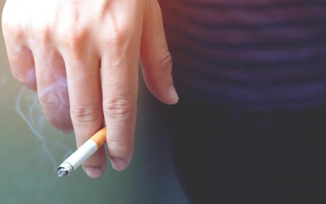 Una mano sostiene un cigarrillo encendido.