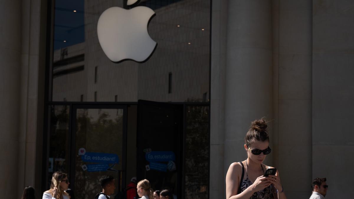 Varias personas caminan frente a una tienda de Apple.