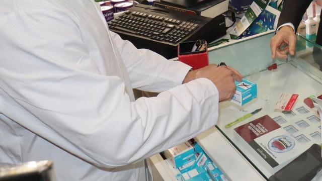 Un farmacéutico recorta el cupón de un medicamento.