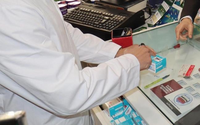 Un farmacéutico recorta el cupón de un medicamento.