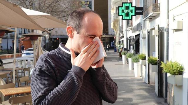 Un hombre estornuda por alergia en la calle