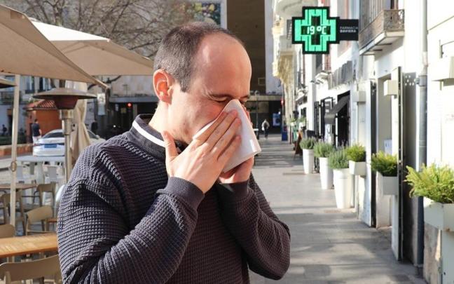 Un hombre estornuda por alergia en la calle