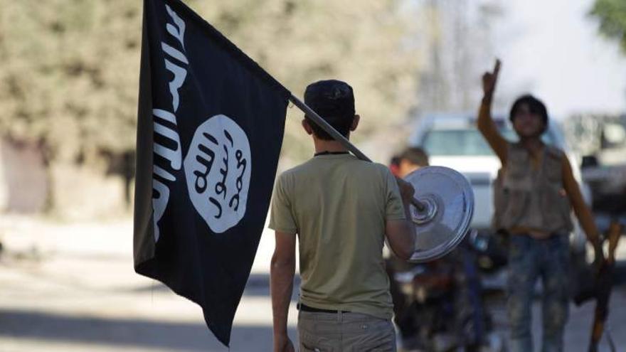 Un joven portando una bandera de Estado Islámico
