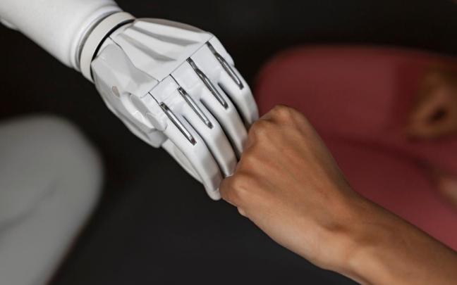La mano de un robot se une a la mano de una humana. La mano de un robot se une a la mano de una humana.
