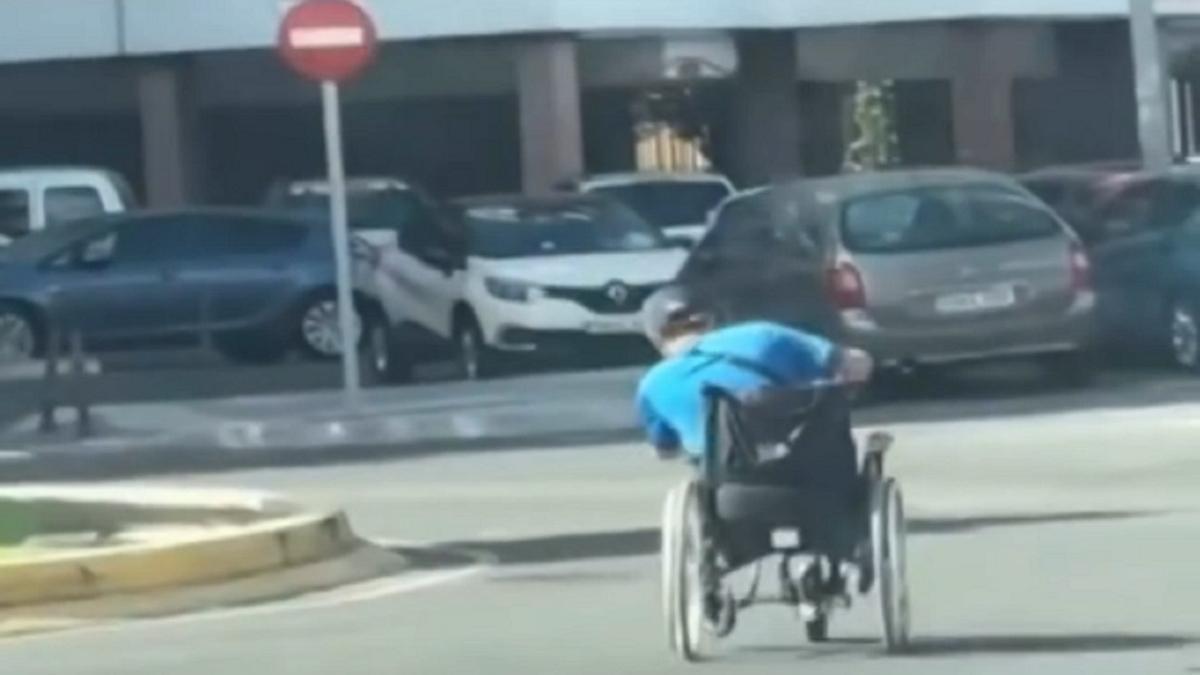 El hombre, inclinándose para tomar mejor la rotonda con la silla de ruedas.