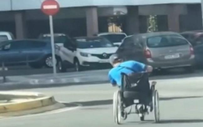 El hombre, inclinándose para tomar mejor la rotonda con la silla de ruedas.