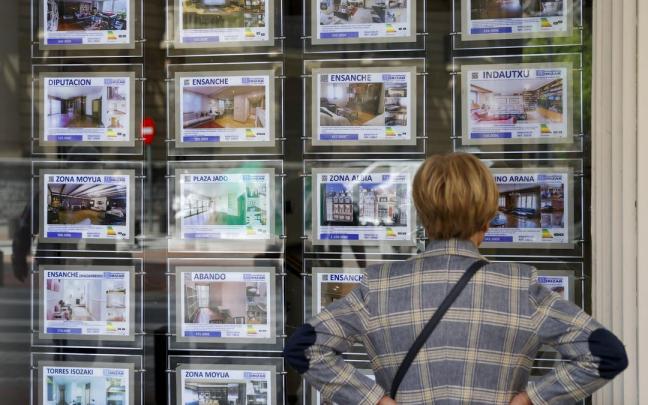 Una mujer mira anuncios de viviendas en una inmobiliaria.