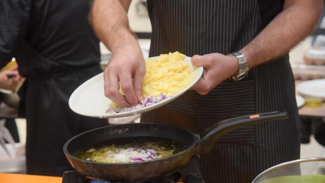 Cocinero prepara una tortilla de patatas con cebolla.