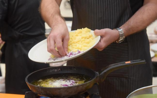 Cocinero prepara una tortilla de patatas con cebolla.