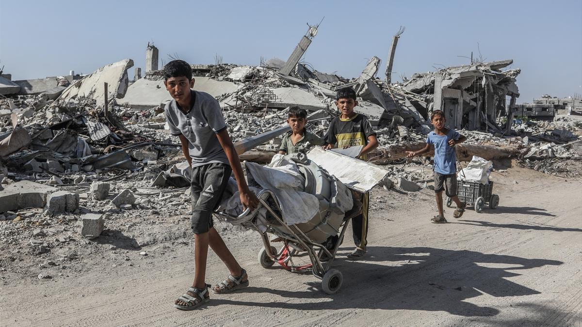 Niños palestinos caminan entre los restos de edificios destruidos mientras regresan a sus hogares, que fueron destruidos por la invasión israelí de la ciudad de Khan Yunis