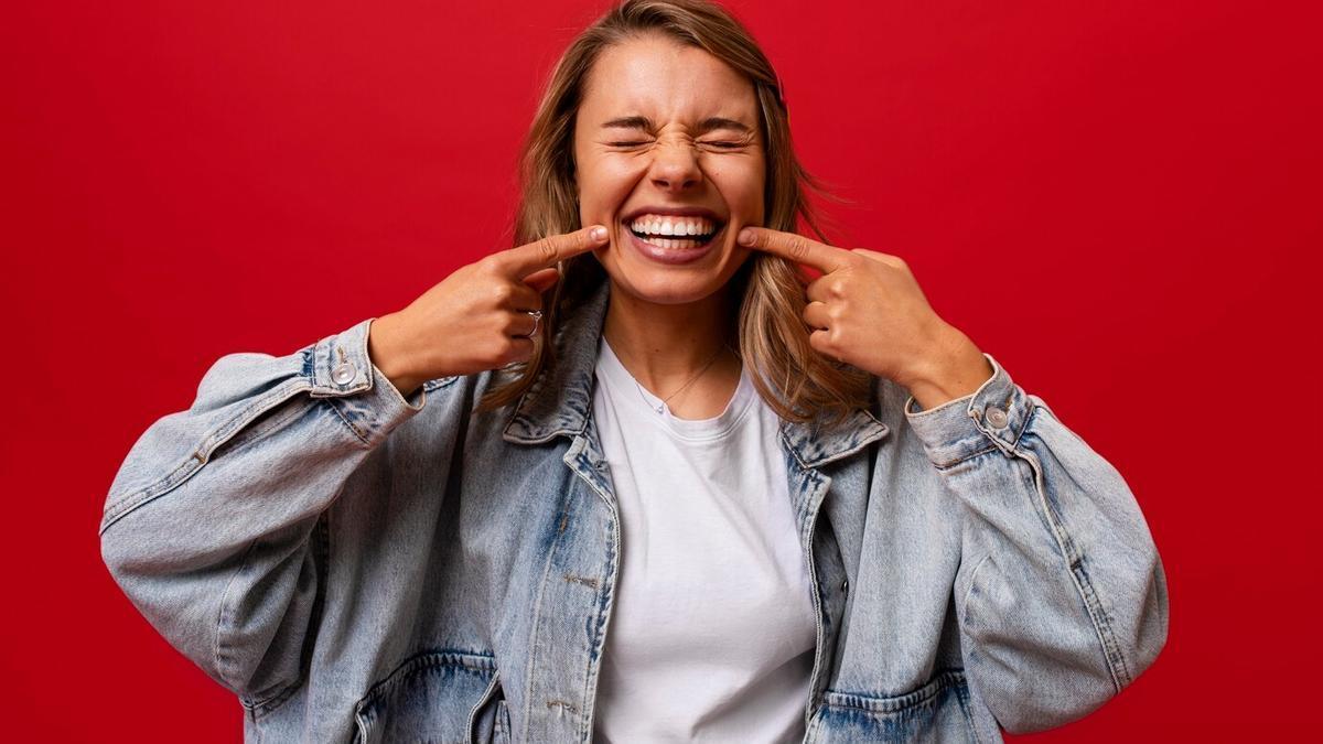 Una mujer muestra una sonrisa forzada.