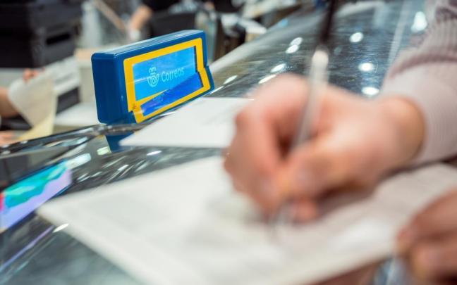 Una persona rellena unos documentos tras solicitar el voto por correo.