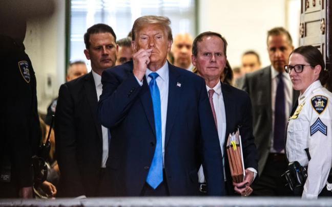 Donald Trump sale de la sala del tribunal e indica a la prensa que todavía está bajo juramento y que no puede hablar.