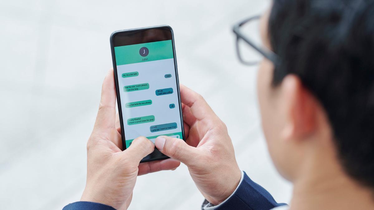 UN joven lee una conversación de WhastsApp.