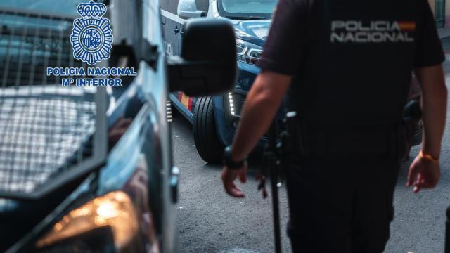Imagen de recurso de un agente de la Policía Nacional junto a dos vehículos policiales.