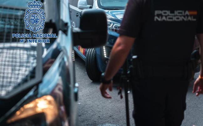 Imagen de recurso de un agente de la Policía Nacional junto a dos vehículos policiales.