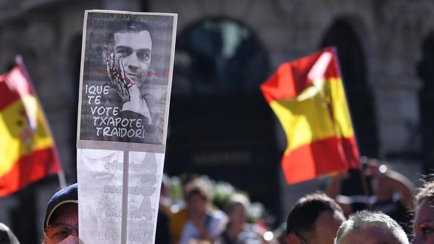 Varias personas portan banderas de España y una pancarta con la imagen del presidente de Gobierno, Pedro Sánchez, en la que se lee "Que te vote Txapote, traidor!".