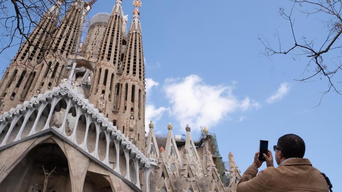 Un turista saca una foto junto a la Sagrada Familia.