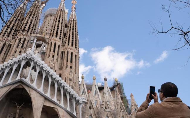 Un turista saca una foto junto a la Sagrada Familia.