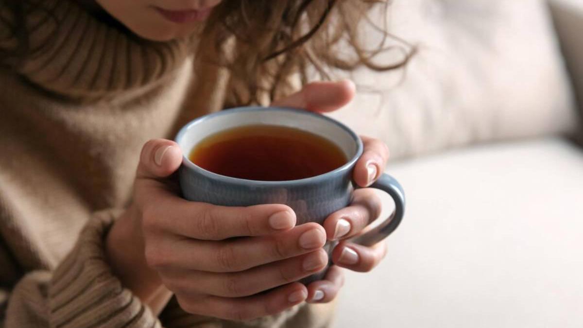 Manos de una chica con una infusión caliente lista para tomar