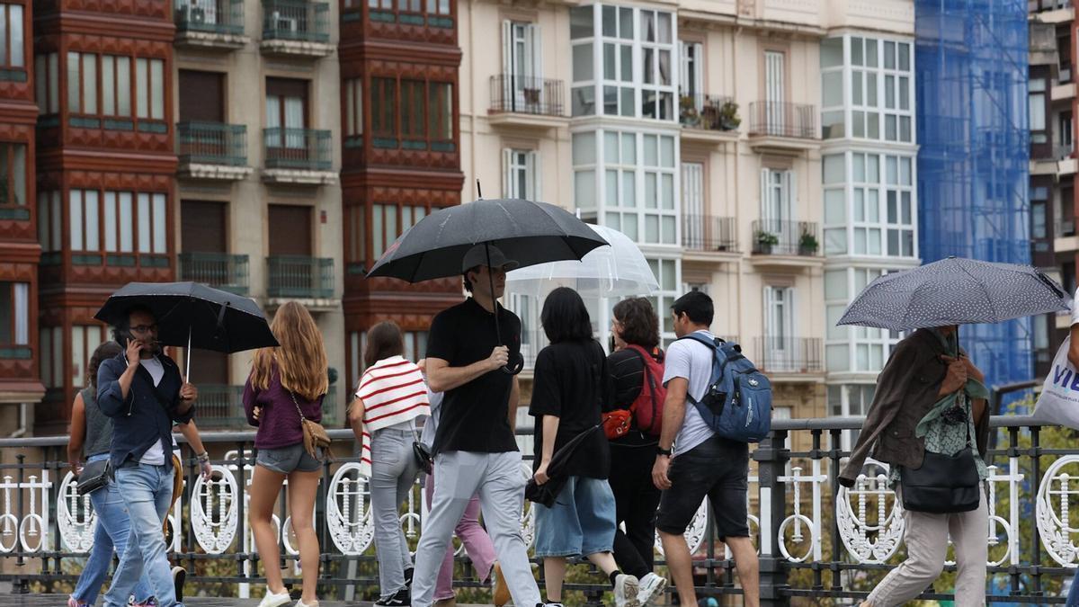 Varias personas caminan bajo la lluvia en Bilbao.