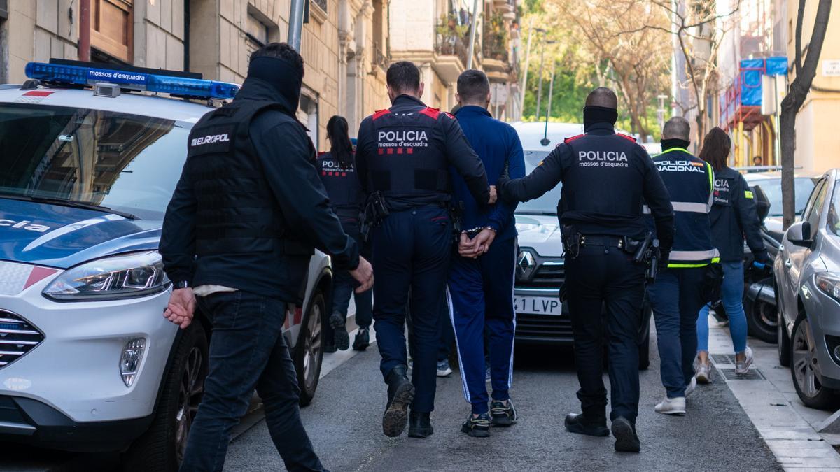 Agentes de los Mossos d'Esquadra se llevan a un detenido durante un operativo policial.