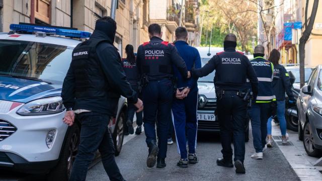 Agentes de los Mossos d'Esquadra se llevan a un detenido durante un operativo policial.