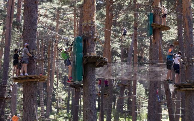 Varias personas recorren los circuitos de un parque de aventuras.