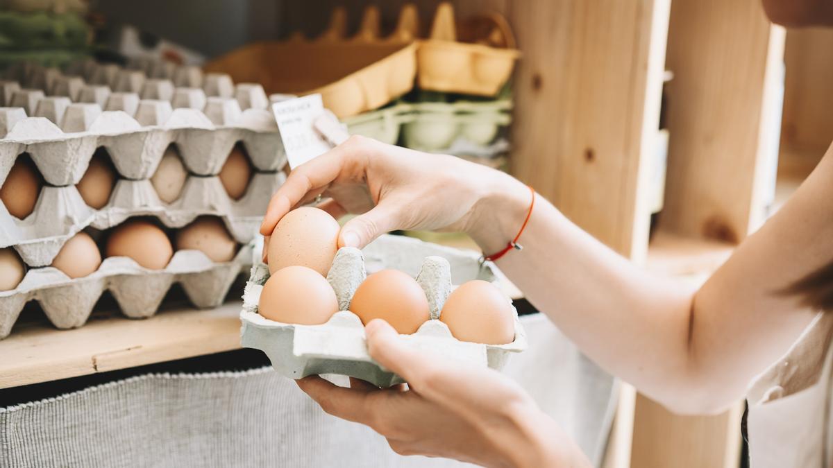 Una mujer selecciona huevos en un comercio.