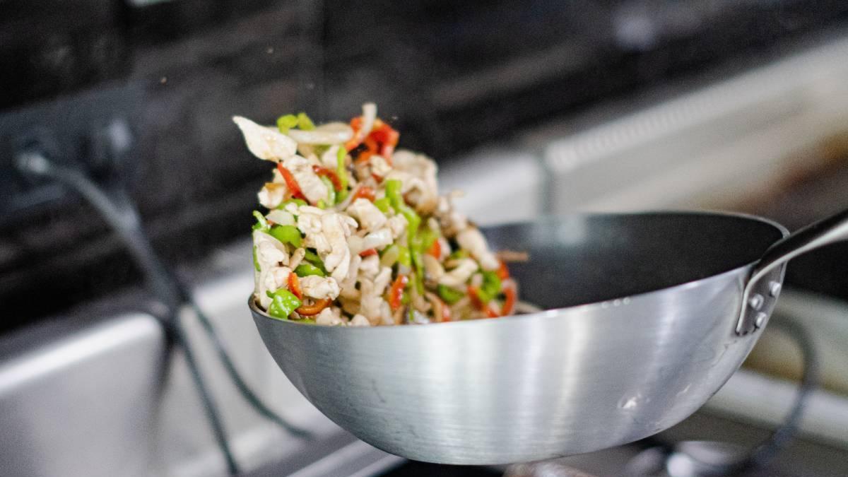Verduras salteadas en una sartén de acero inoxidable.