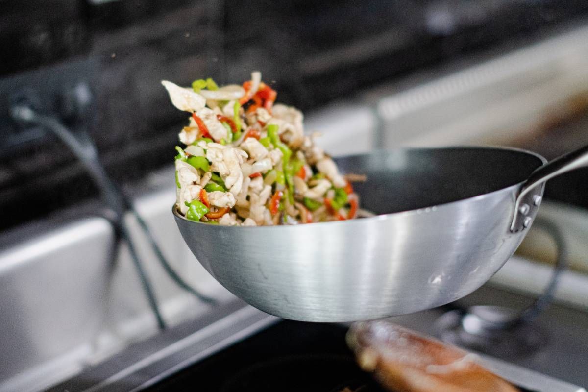 Verduras salteadas en una sartén de acero inoxidable.