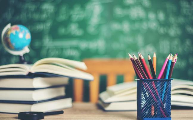 Mesa de escuela con libros y pinturas de colores.