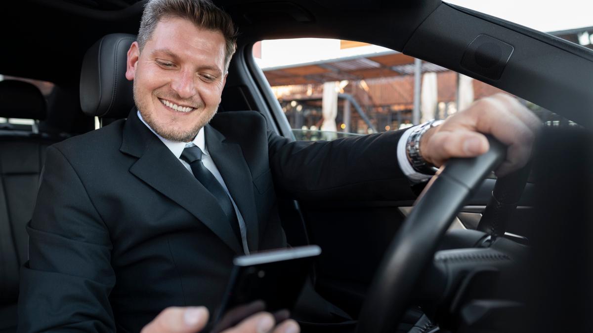 Un conductor consulta su móvil a la espera de un cliente o de una 'microtareas digital'.