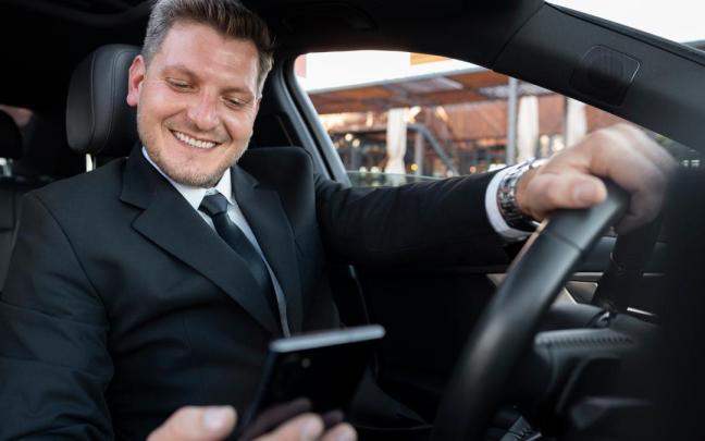 Un conductor consulta su móvil a la espera de un cliente o de una 'microtareas digital'.