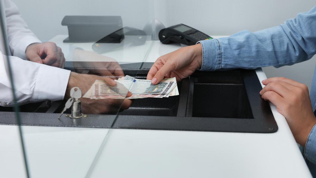 Una persona realiza una operación en efectivo en su entidad financiera.