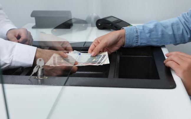 Una persona realiza una operación en efectivo en su entidad financiera.