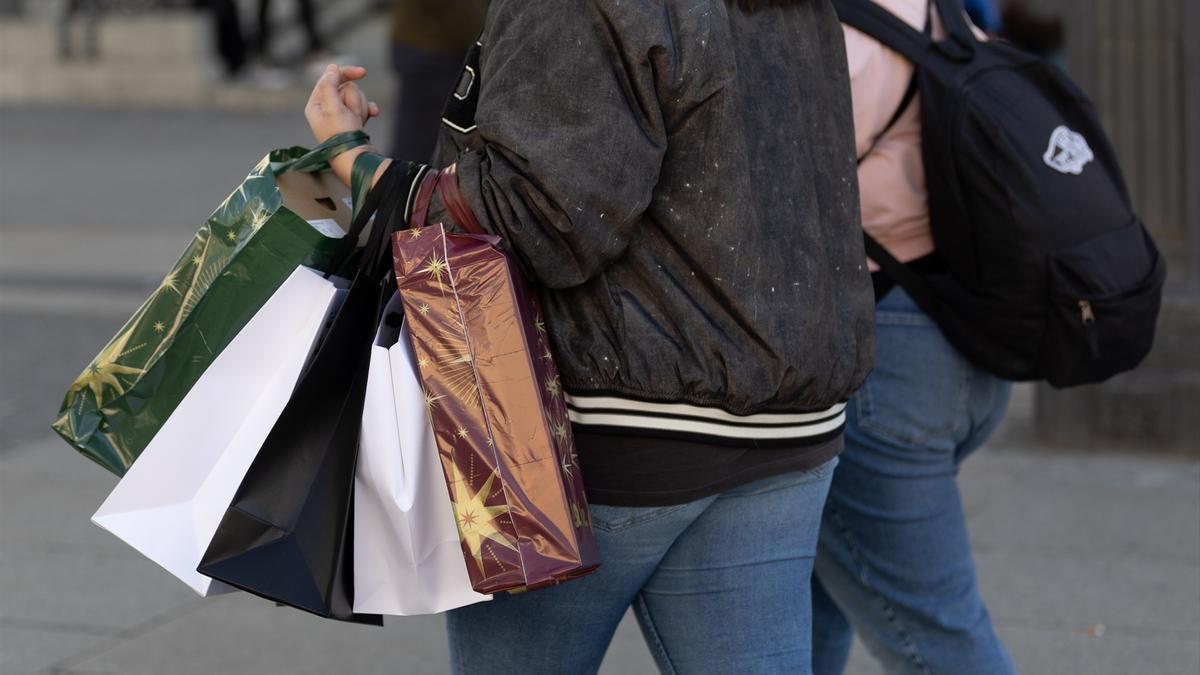 Una persona lleva varias bolsas de compra durante Black Friday.