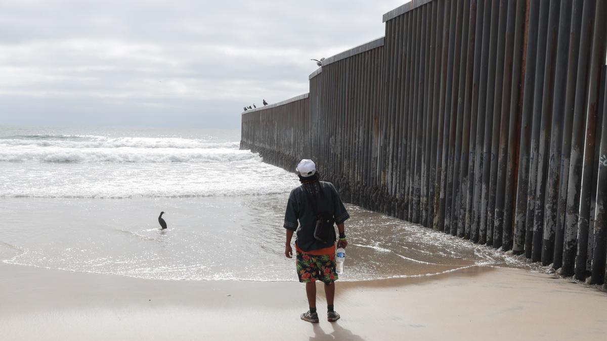 Un migrante junto al muro que separa México y Estados Unidos.