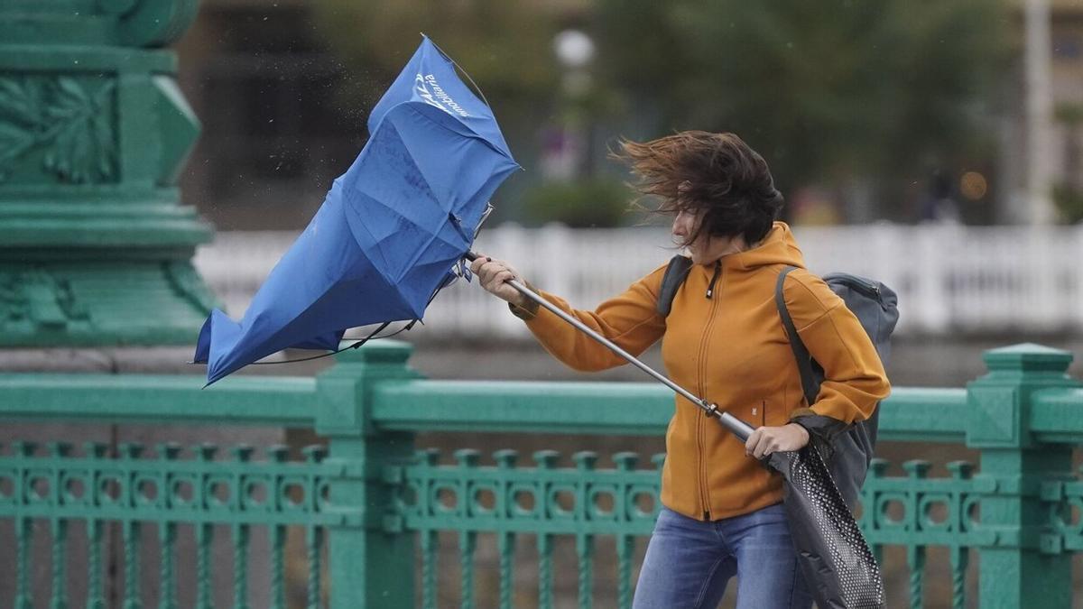 Imagen de archivo de una mujer "luchando" con su paraguas contra el viento