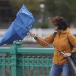 Imagen de archivo de una mujer "luchando" con su paraguas contra el viento