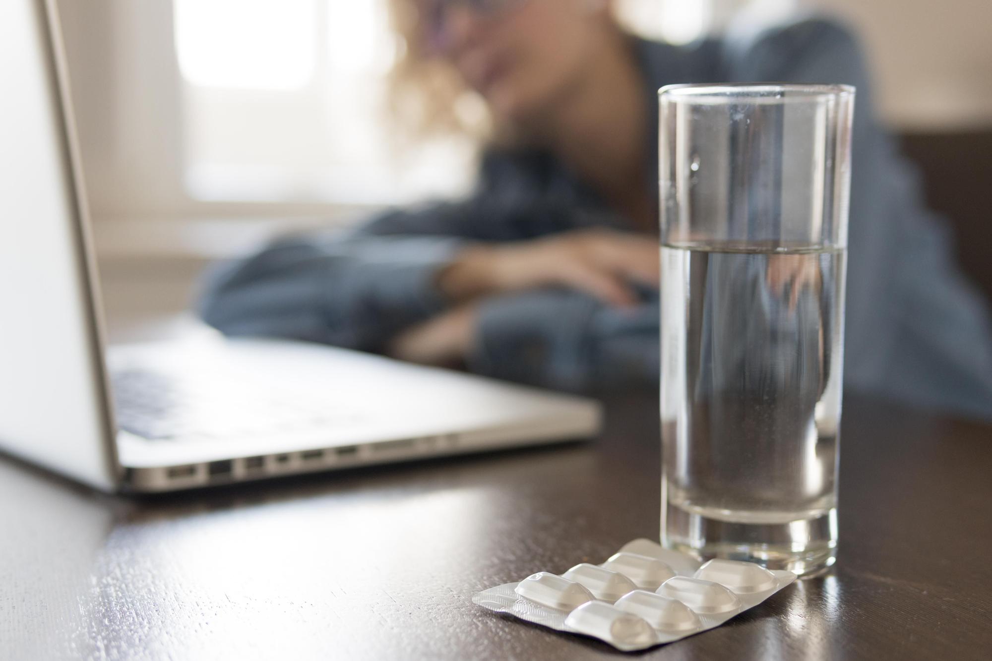 Ibuprofeno al lado de un vaso de agua
